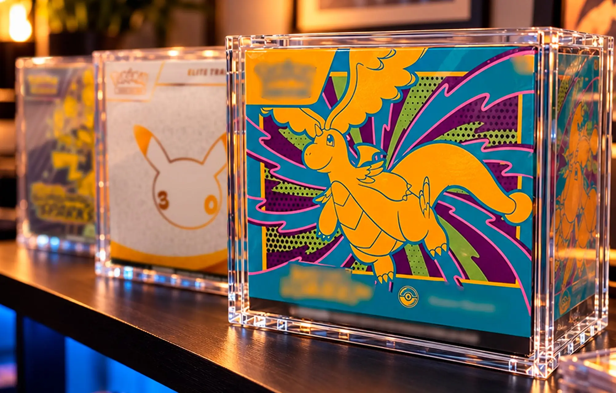 Elite Trainer Boxes displayed in Slab Bunker acrylic cases on a shelf